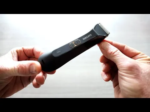 Manscaped Lawn Mower trimmer held horizontally in two hands over a bright surface, showcasing its matte black finish and ergonomic design