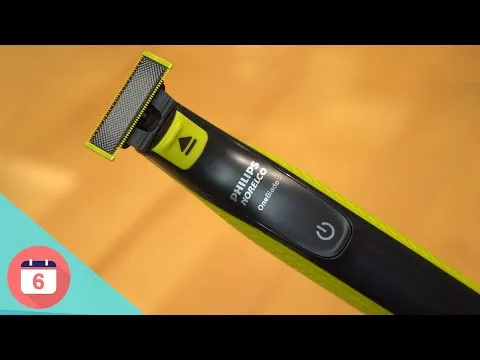 Close-up of the Philips Norelco OneBlade trimmer resting on an orange surface detailing the blade head, logo, and textured green handle
